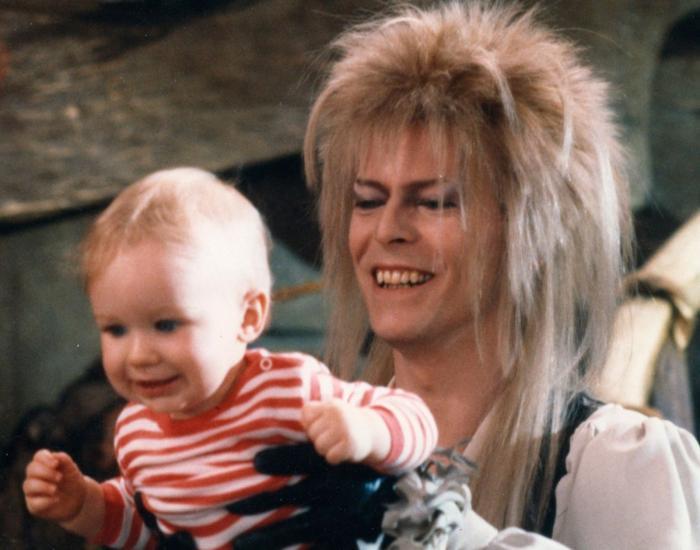 David Bowie gleefully holds a baby at arm's length