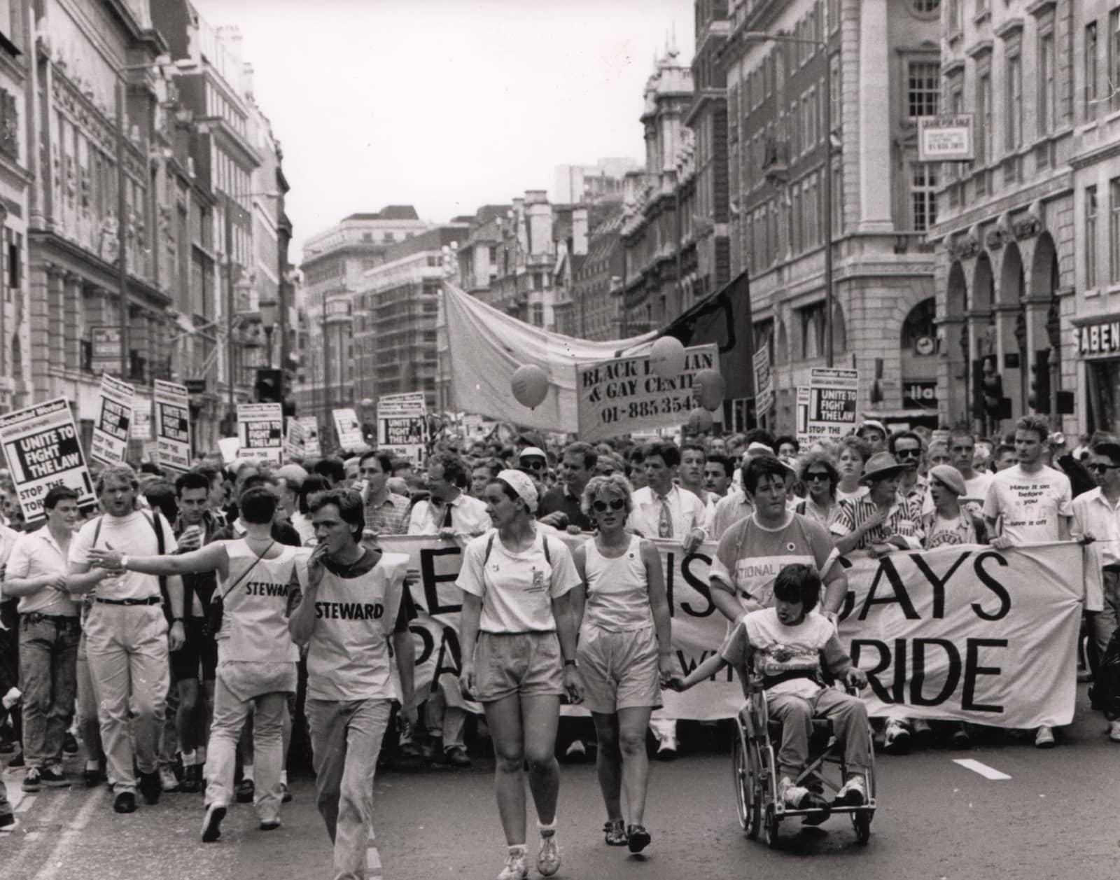 A black and white photo from the 1970s/80s showing a protest walk of many people