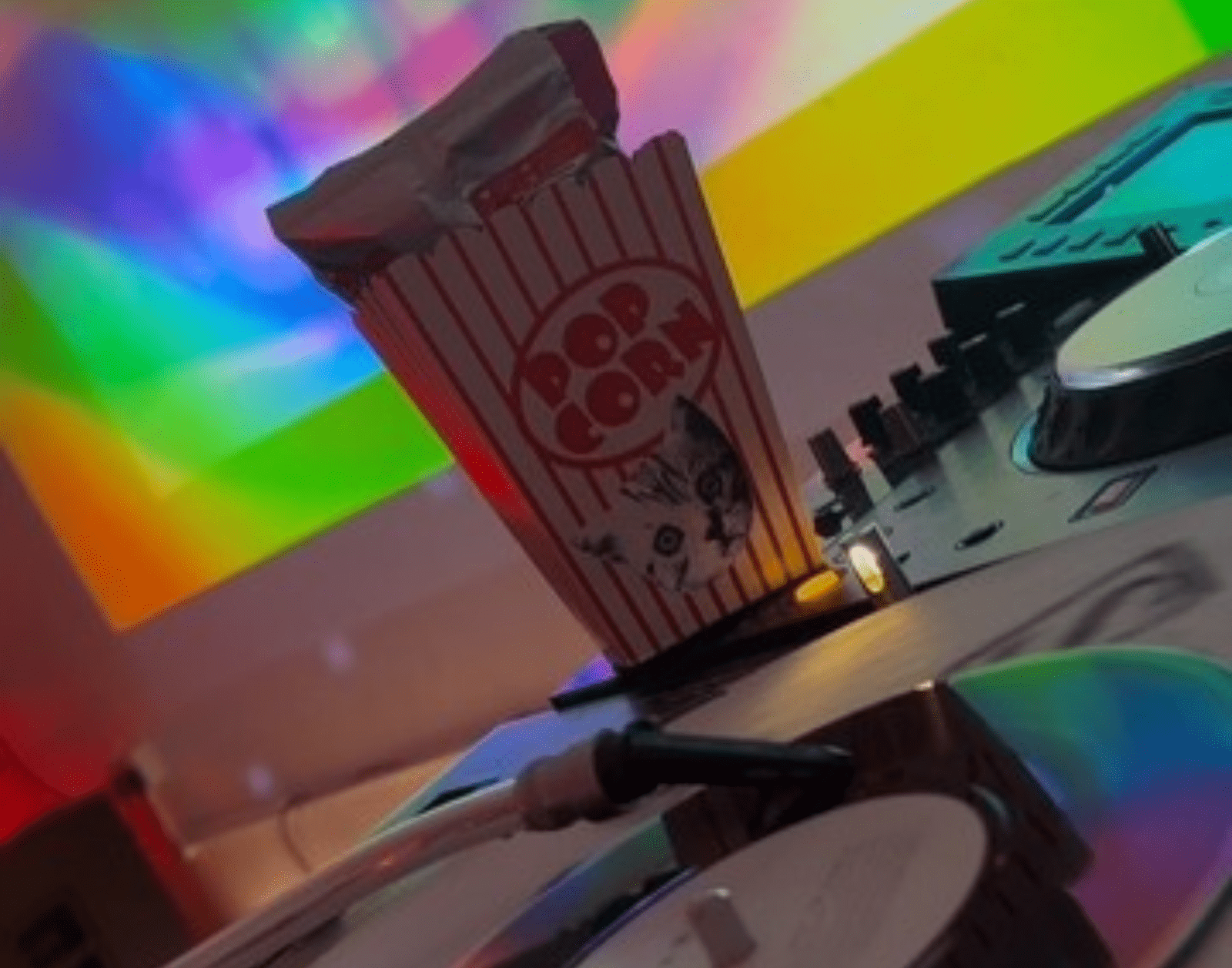 a vinyl record spins in a room with disco lights on a wall there's a projected image of rainbow lips