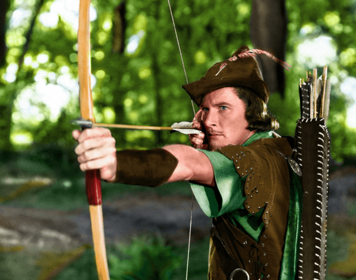 Errol Flynn holds a bow and arrow in character as Robin Hood