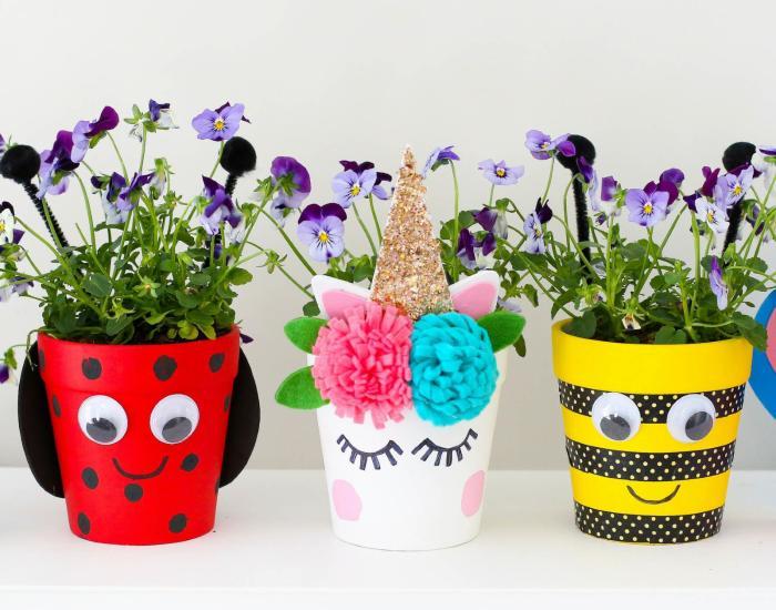 A row of hand-decorated plant pots with flowers planted inside