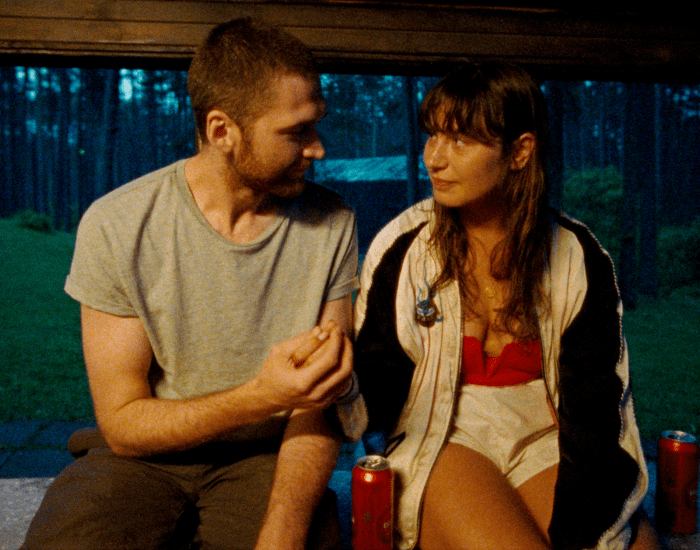 A young couple sit looking at each other affectionately